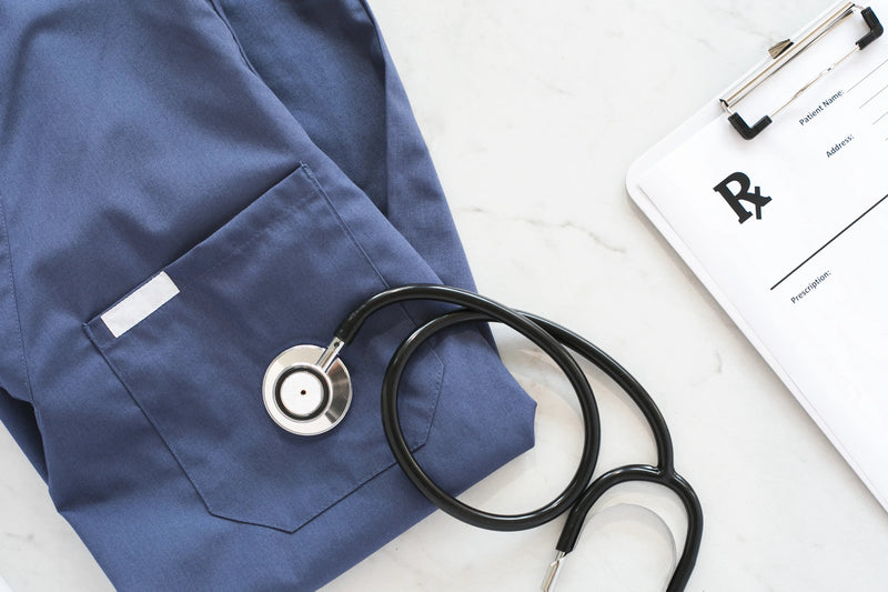 Blue medical coat with stethoscope and clipboard on a white surface